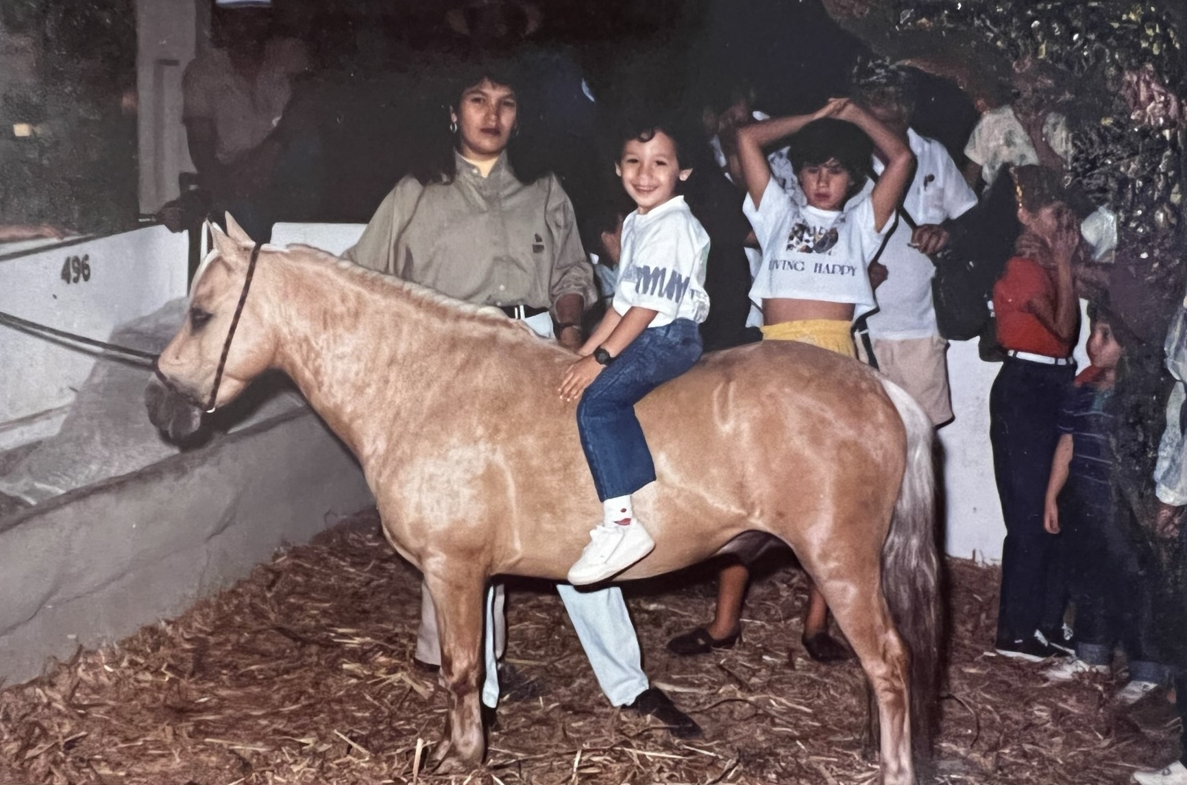 Photo of Julian from childhood with his mom. Julian sits on a horse