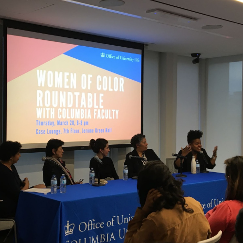 Five women in panel discussion - students listening