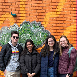 Four students in front of mural