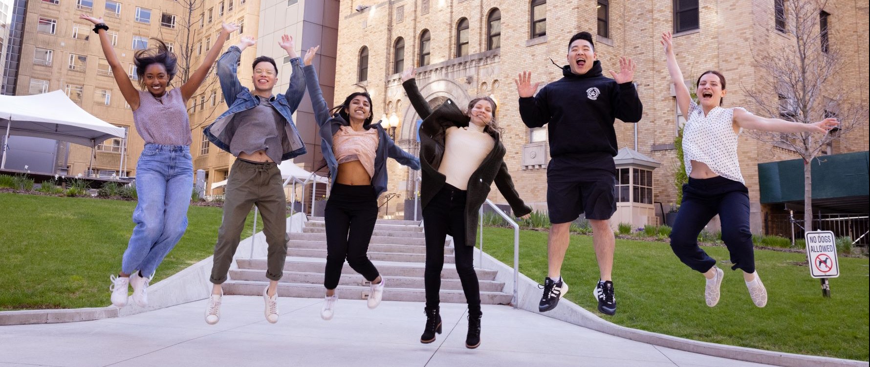students jumping and posing for a photo in front of the Mailman School of Public Health