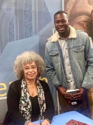 James with Angela Davis at the UCLA Black Alumni Association's Social Justice Summit with Jemele Hill and Common. Image of James holding book and Standing behind Angela Davis