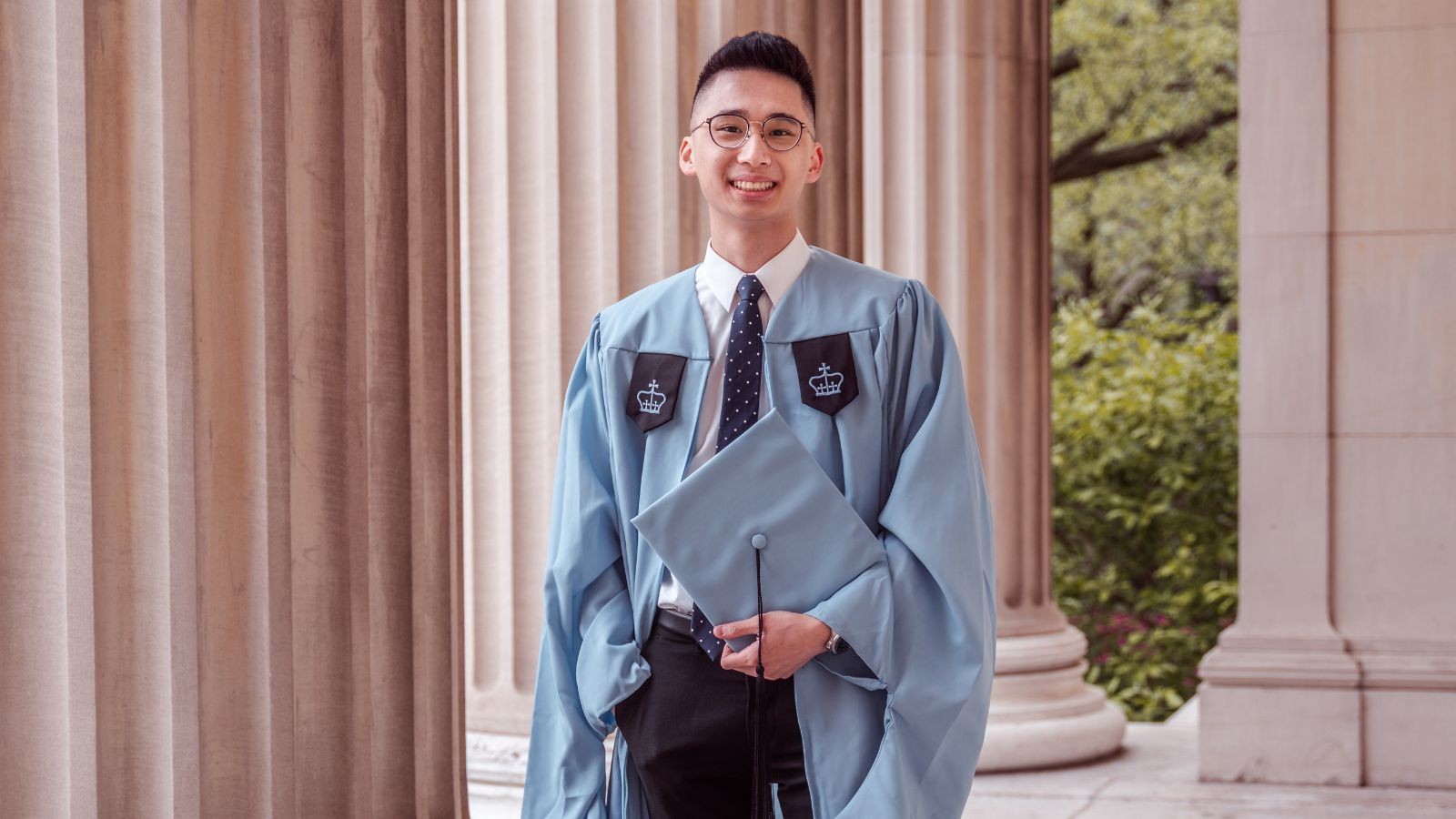 Jeremy in graduation gown poses on the Morningside C