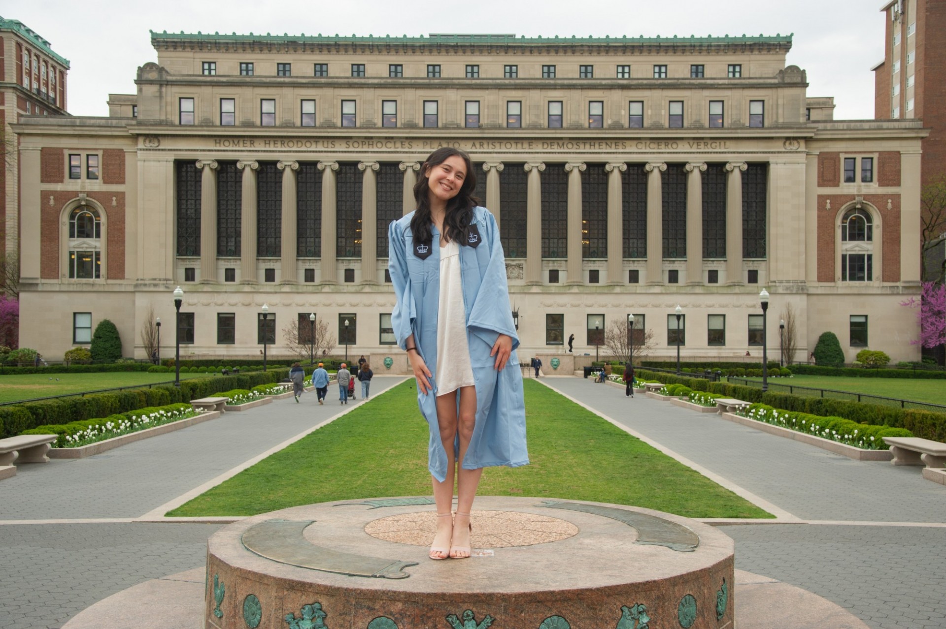 Maya standing on the sundial in graduation gown