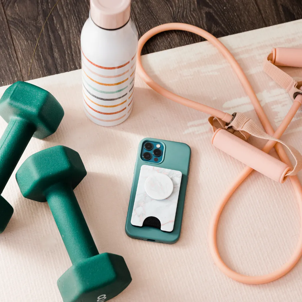 Weights, a cellphone, water bottle, and jump rope lay on a yoga mat together
