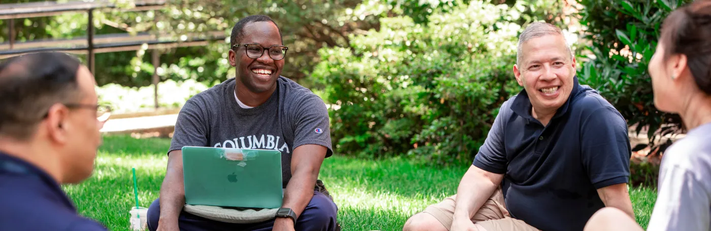 Four Students Sit in Grass Talking