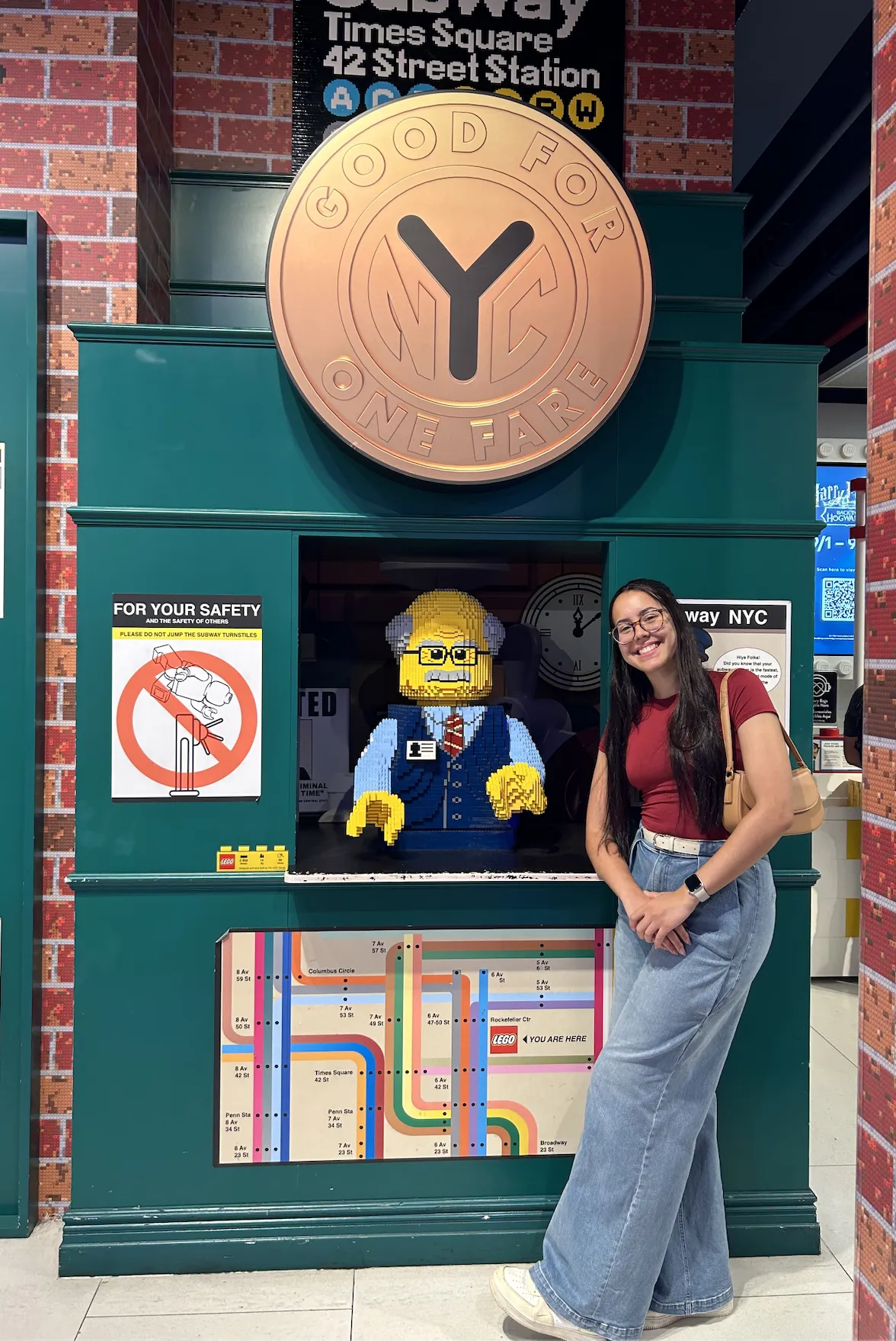 Marina Martins posing in front of a LEGO statue in one of the city's subway stations