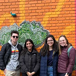 Four students in front of mural