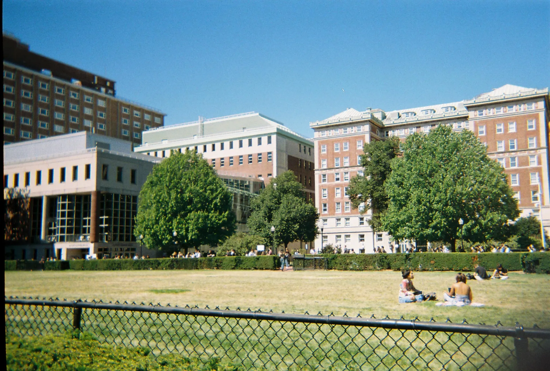 Inside of the Columbia main campus with two people sitting on the grass on the right of the picture
