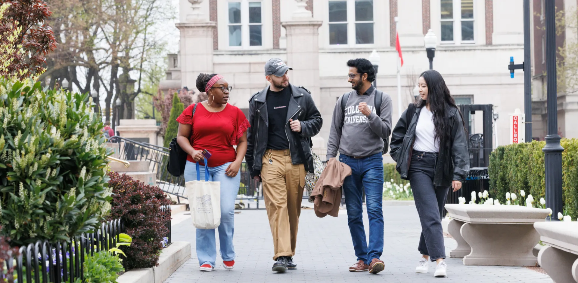 Four students walking and talking together on the Columbia Morningside campus