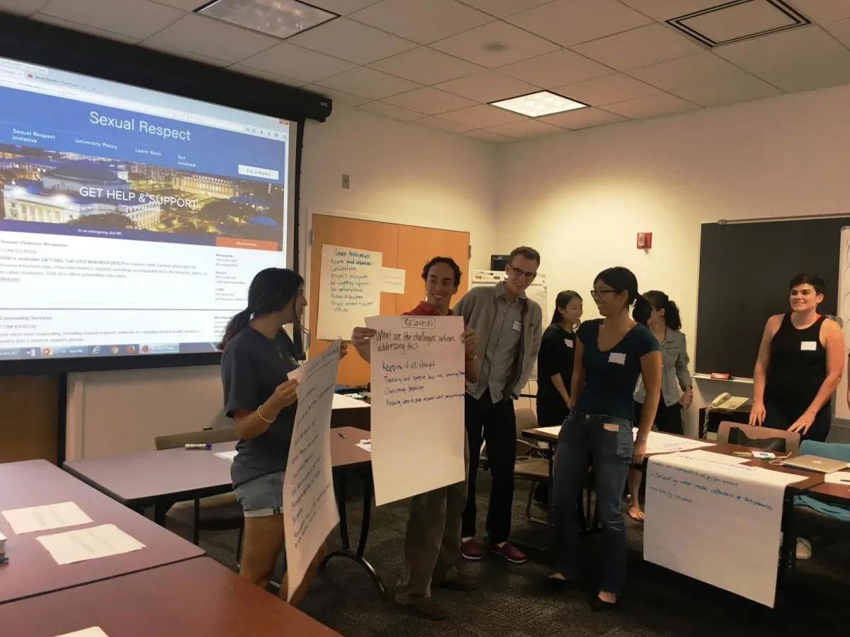 people in front of classroom holding large papers
